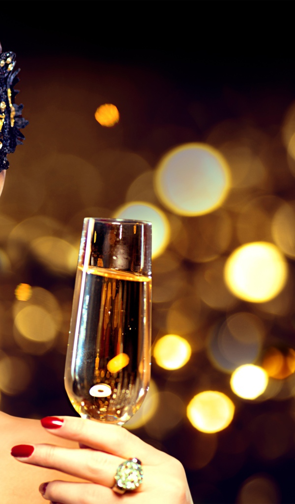 Красивая девушка в черной маске с бокалом шампанского