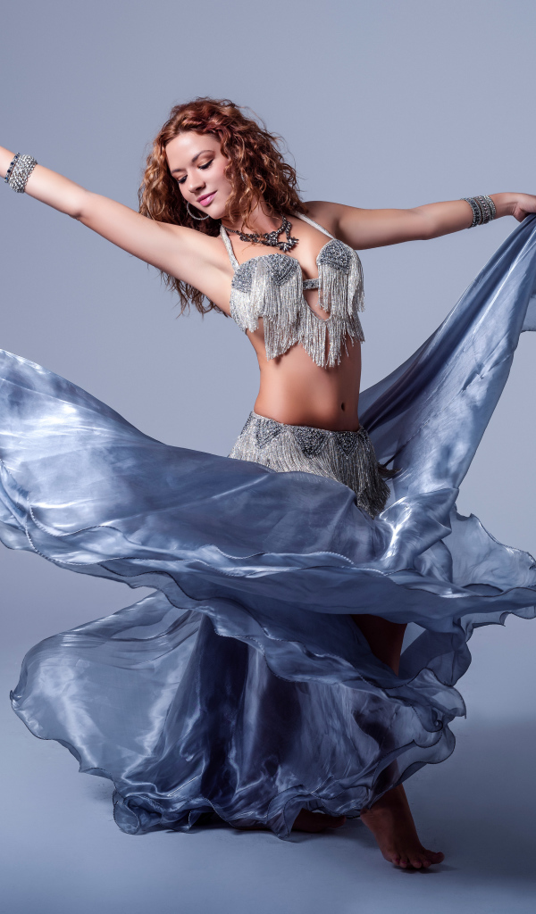 Красивая девушка в платье для танцев на сером фоне