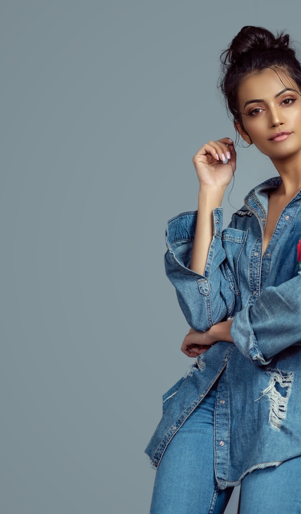 Красивая девушка в джинсовом костюме на сером фоне