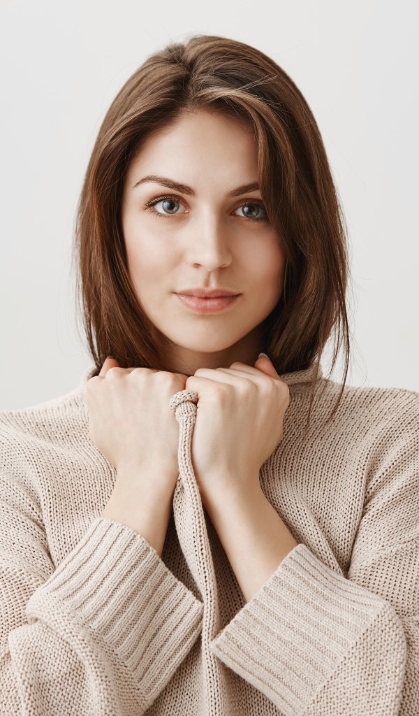 Красивая девушка в теплом свитере на сером фоне 