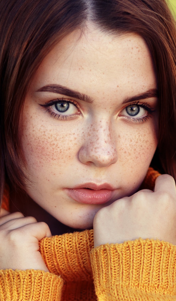 Красивая девушка в теплом свитере с веснушками на лице