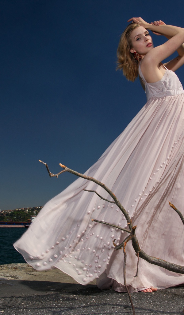 Красивая девушка в белом платье на берегу реки