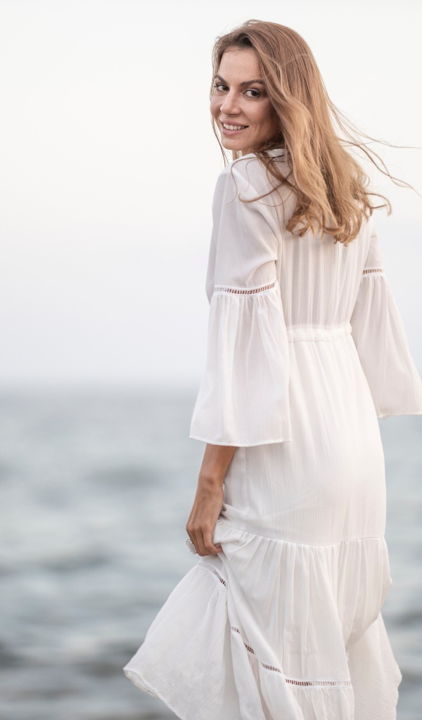 Красивая девушка в белом платье у моря