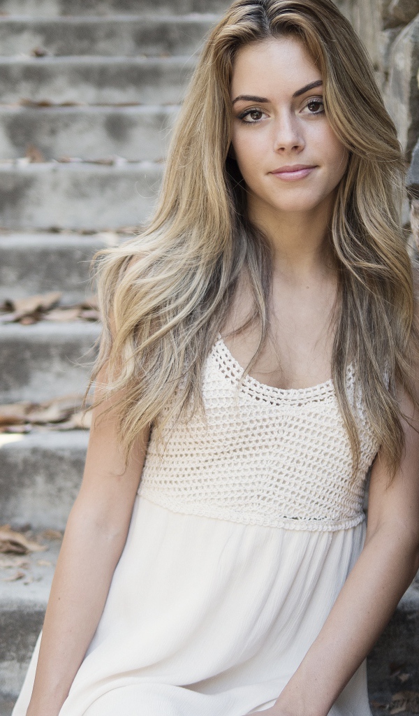 Красивая девушка в белом платье у каменной стены 