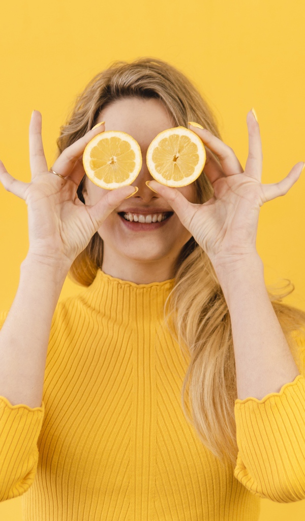 Красивая девушка в желтом свитере с лимоном