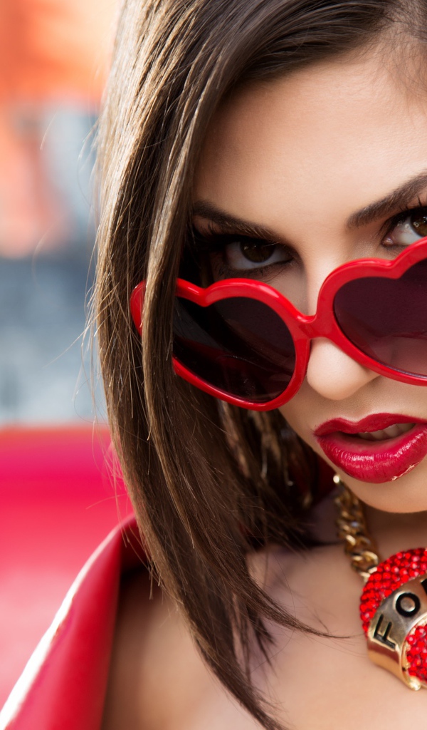 Красивая девушка в красных очках с украшением на шее 