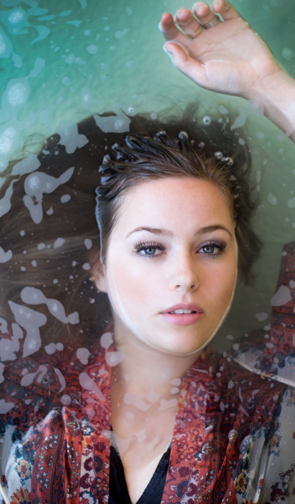 Красивая девушка лежит в одежде в воде 