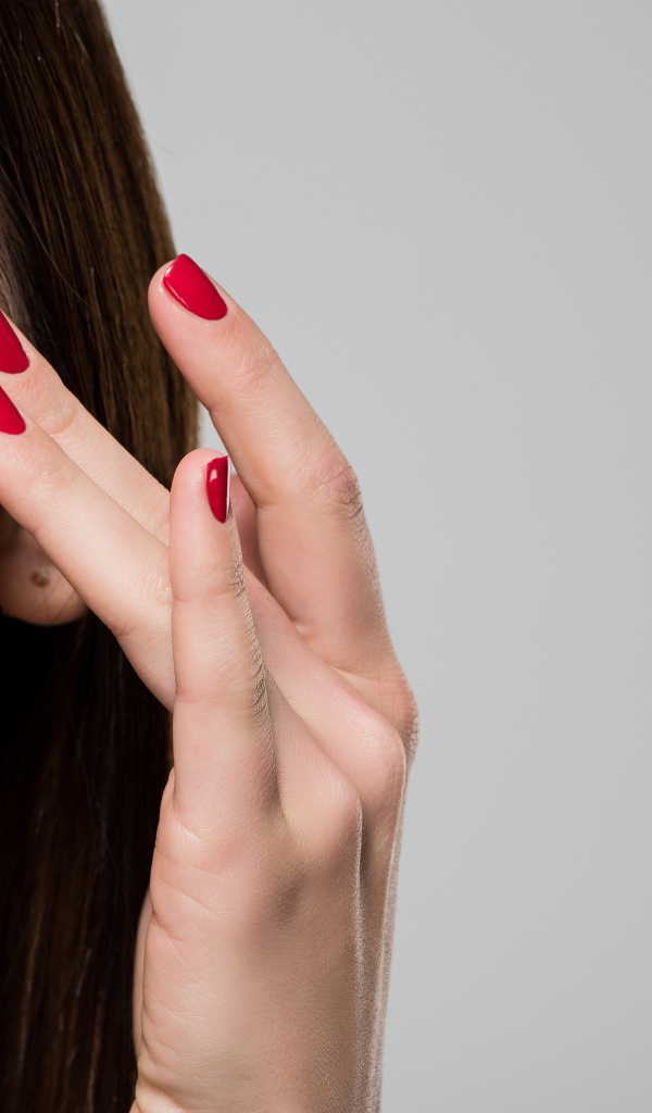 Красивая девушка модель мажет лицо кремом на сером фоне 