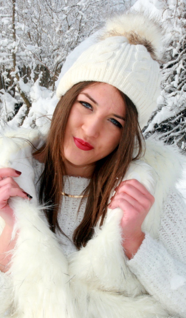 Красивая девушка на фоне заснеженных деревьев зимой