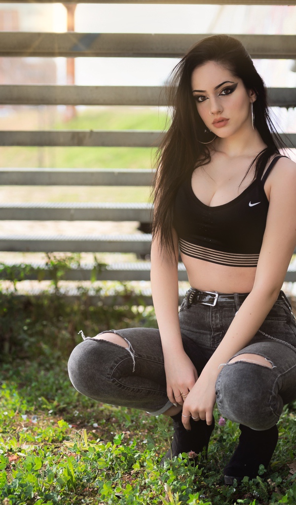 Красивая девушка сидит под лестницей 