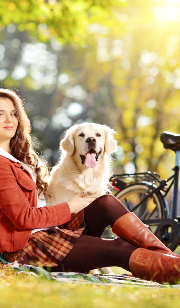 Красивая девушка сидит с собакой у дерева 