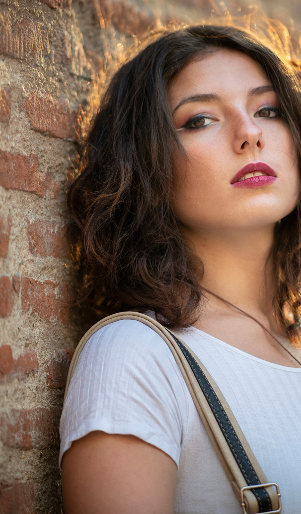 Красивая девушка стоит у стены 