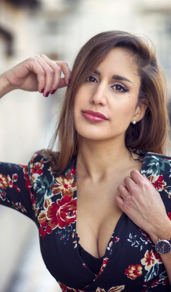 Красивая девушка с часами на руке стоит у стены