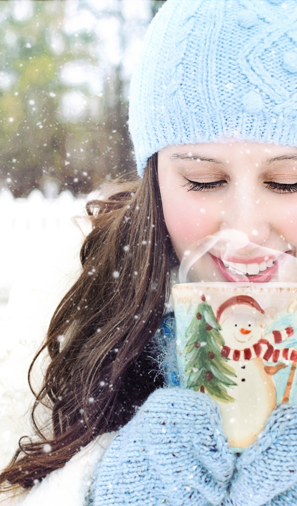 Красивая девушка с чашкой горячего кофе на улице зимой