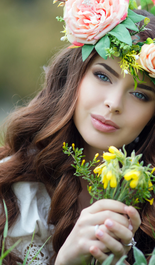 Красивая девушка с венком на голове лежит на зеленой траве