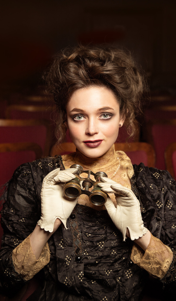 Красивая девушка с биноклем сидит в театре