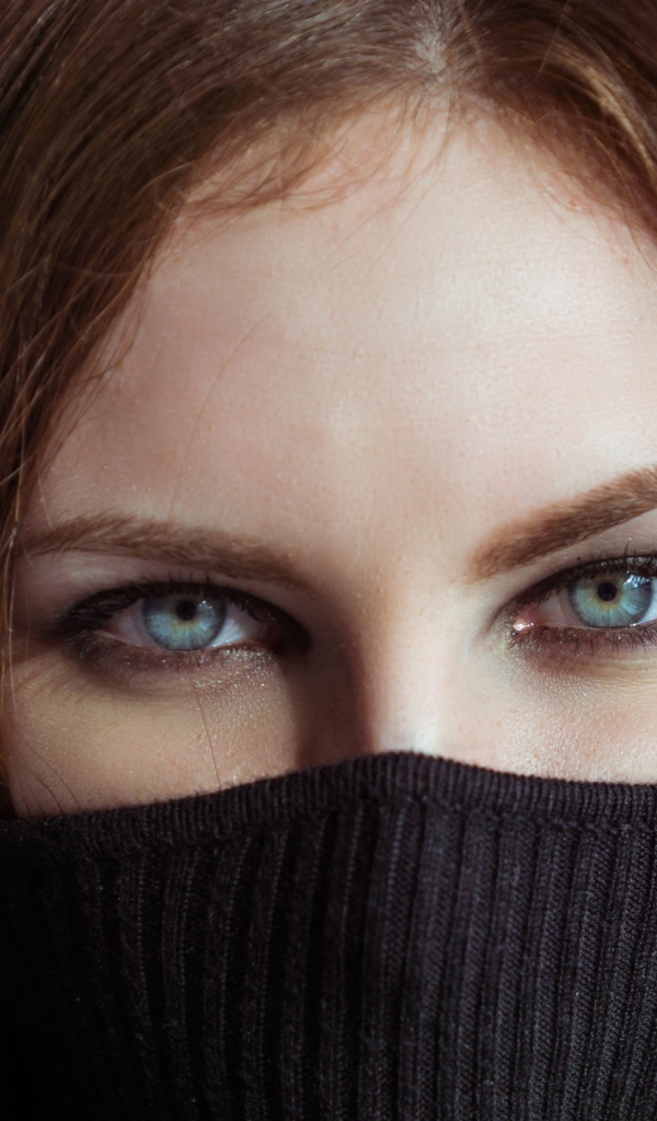 Красивая девушка с голубыми глазами закрыла лицо свитером 