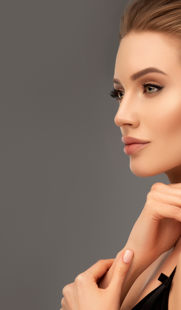 Красивая девушка с вечерней прической на сером фоне