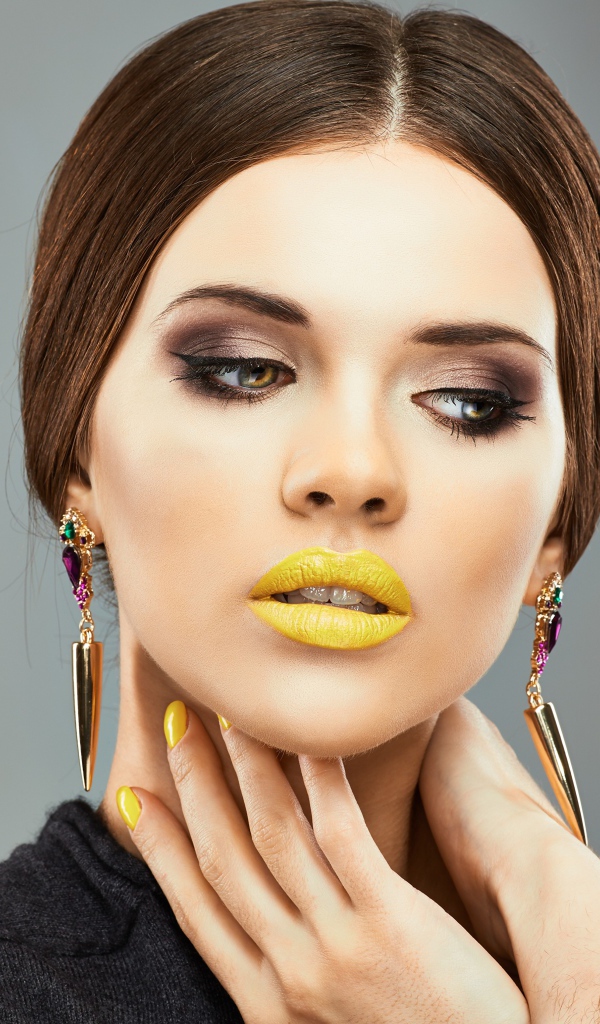 Красивая девушка с дорогими серьгами в ушах на сером фоне