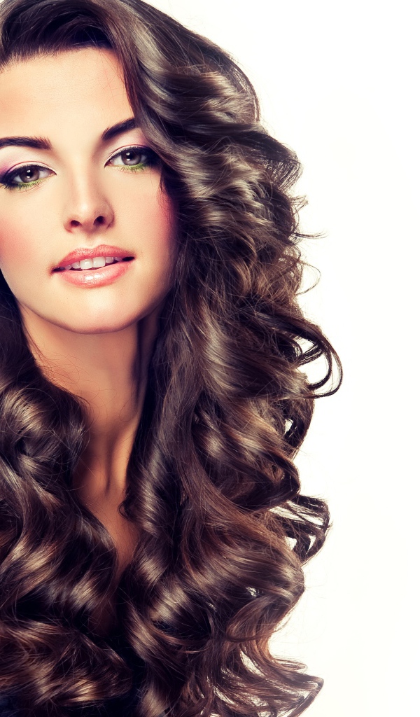 Красивая длинноволосая девушка с цветком в волосах на белом фоне