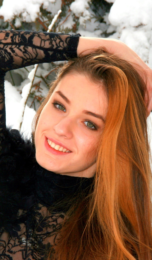 Красивая рыжеволосая девушка у заснеженной туи