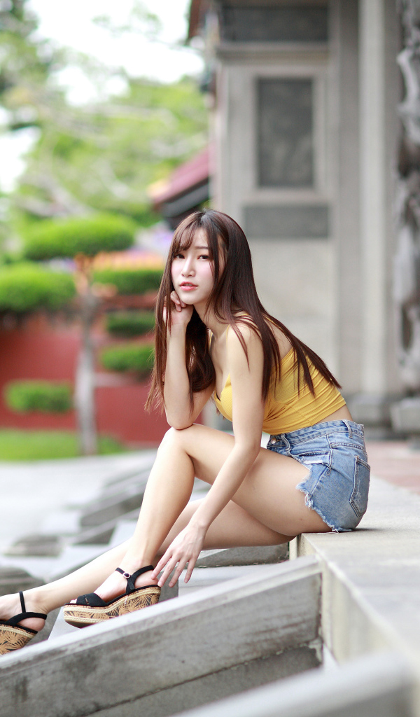 Красивая молодая девушка азиатка сидит на ступеньках 