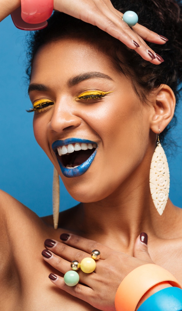 Красивая молодая девушка с ярким разноцветным макияжем на голубом фоне