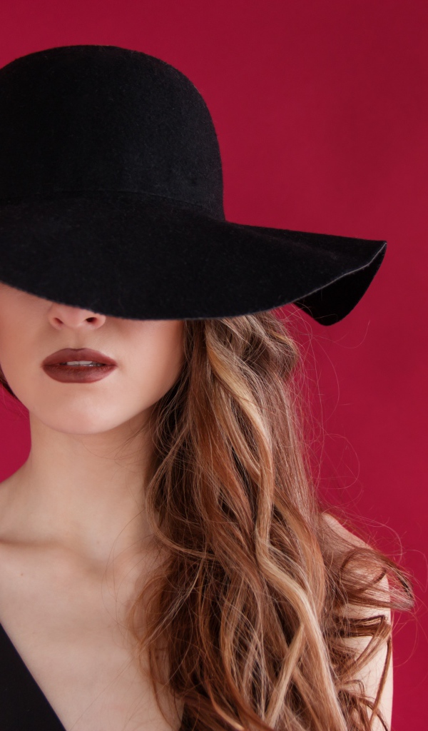Большая черная шляпа закрывает лицо девушки