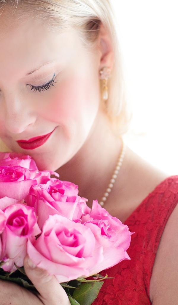 Блондинка с закрытыми глазами нюхает букет роз