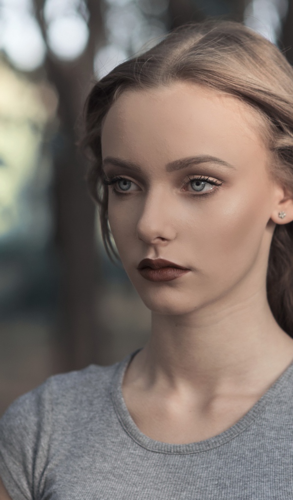 Голубоглазая девушка в серой майке в парке 