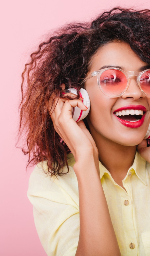 Яркая улыбающаяся девушка слушает музыку в наушниках 