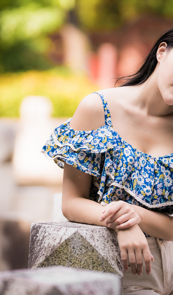 Кареглазая азиатка в яркой кофте в парке 