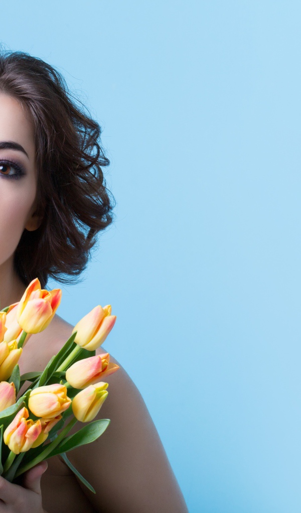 Кареглазая шатенка с букетом тюльпанов на голубом фоне