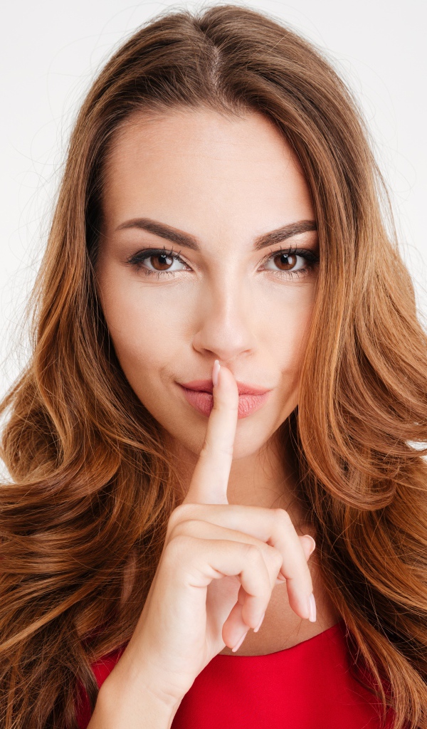 Кареглазая длинноволосая девушка держит палец у губ 