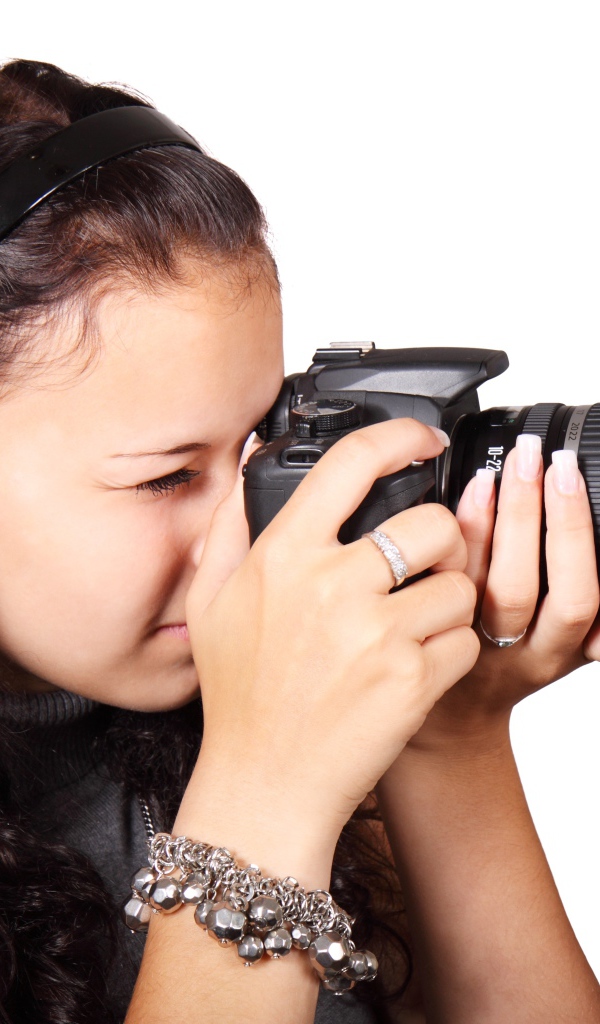 Молодая девушка шатенка с фотоаппаратом в руках на белом фоне