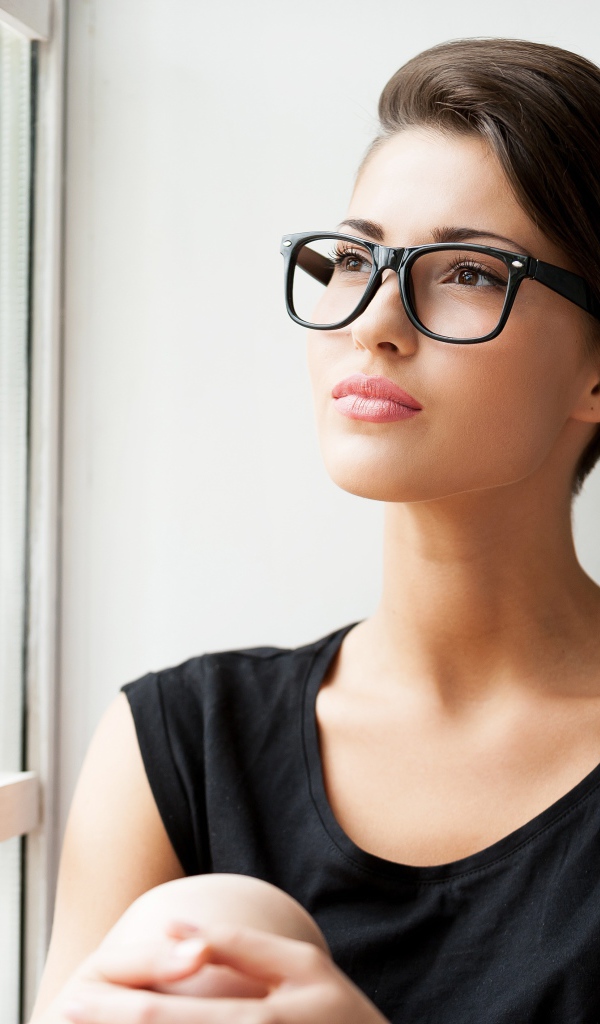 Деловая девушка в очках сидит у окна 