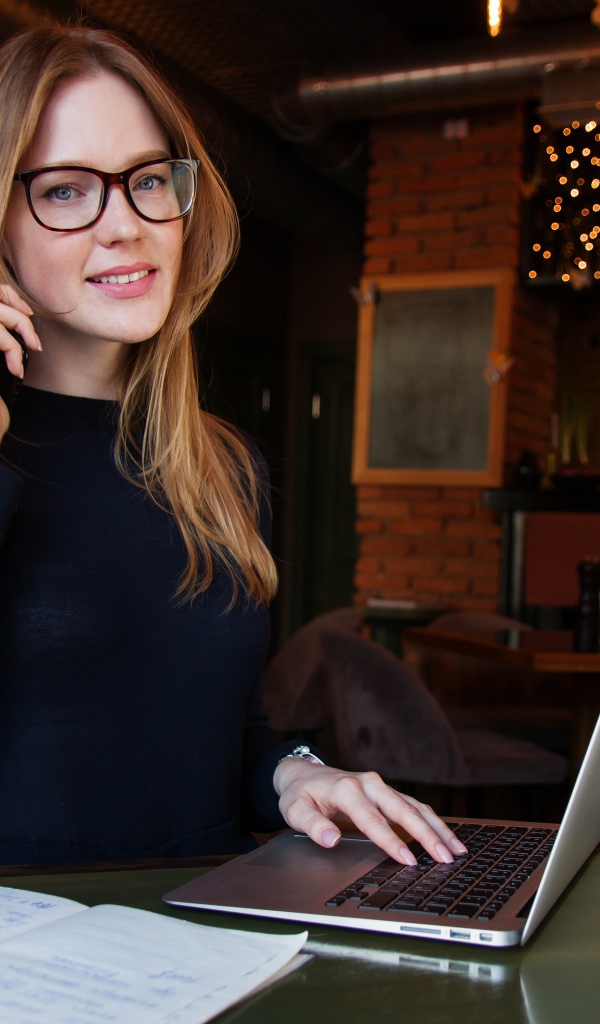 Деловая девушка в очках сидит с кафе с ноутбуком