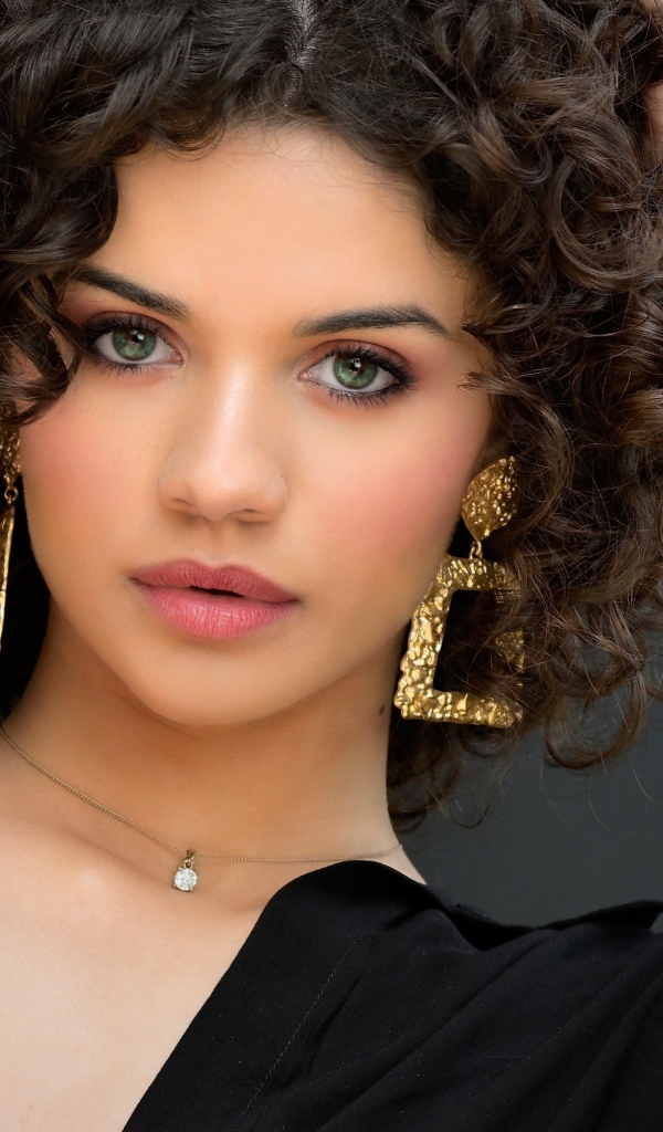 Кудрявая девушка с рукой в волосах в черной рубашке 