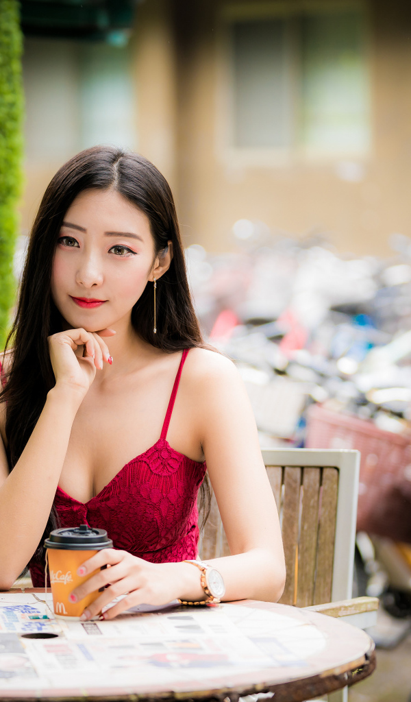 Милая девушка азиатка сидит за столиком в кафе