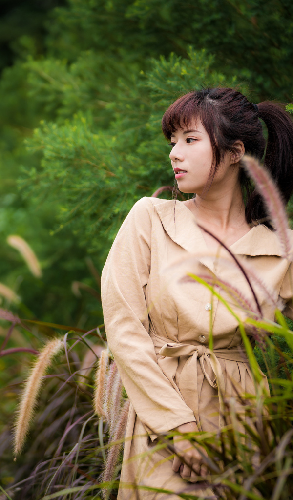 Милая азиатка в пальто в парке 