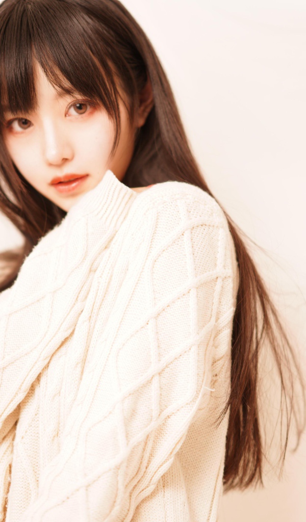 Милая азиатка в белом свитере на розовом фоне