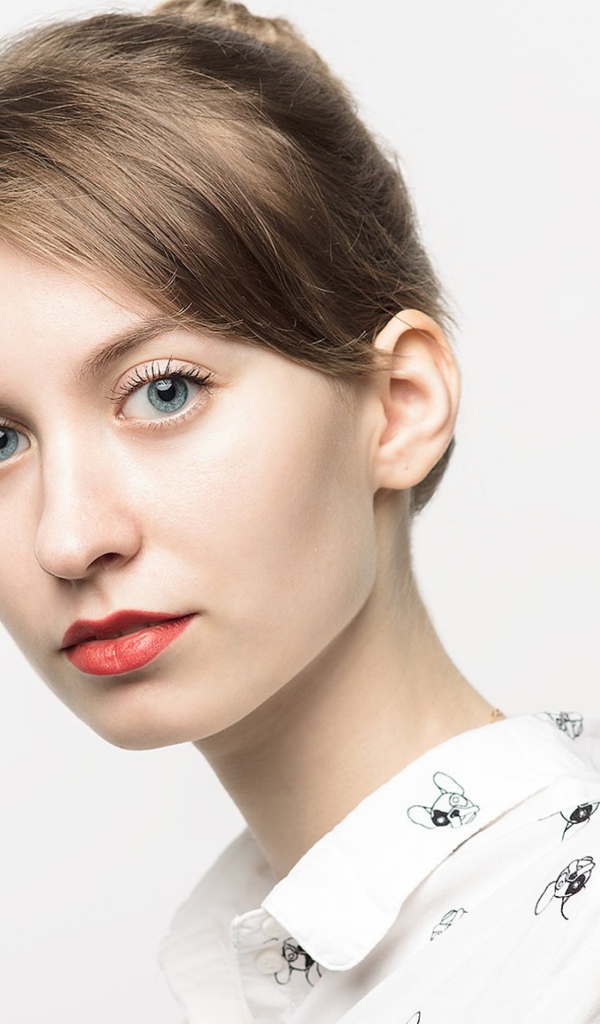 Милая голубоглазая девушка в рубашке на сером фоне