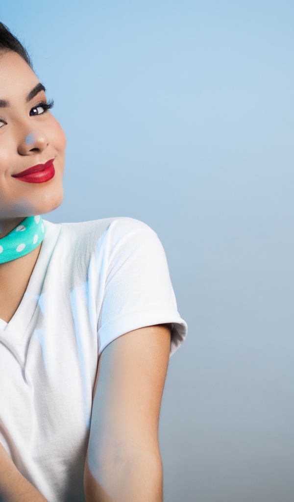 Милая улыбающаяся девушка с шарфом на шее на сером фоне