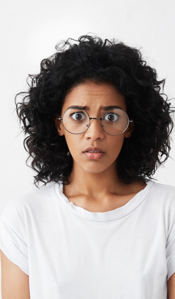 Темноволосая девушка в белой футболке на сером фоне