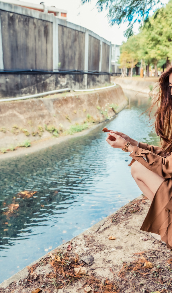 Мечтательная девушка азиатка сидит у воды