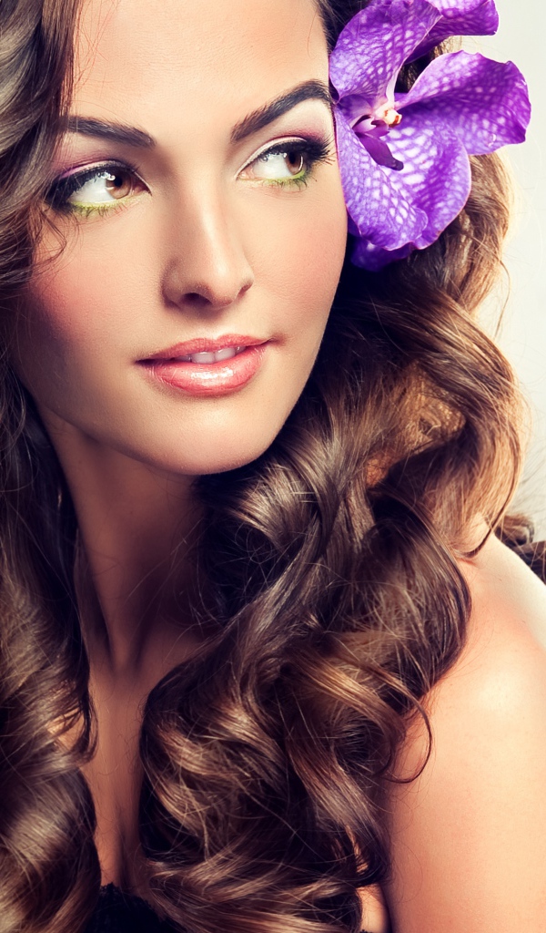 Цветок в красивых длинных волосах молодой девушки