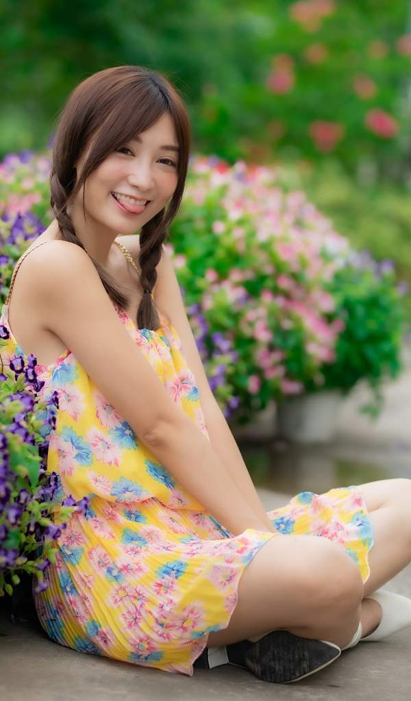 Смешная девушка азиатка в платье сидит на земле