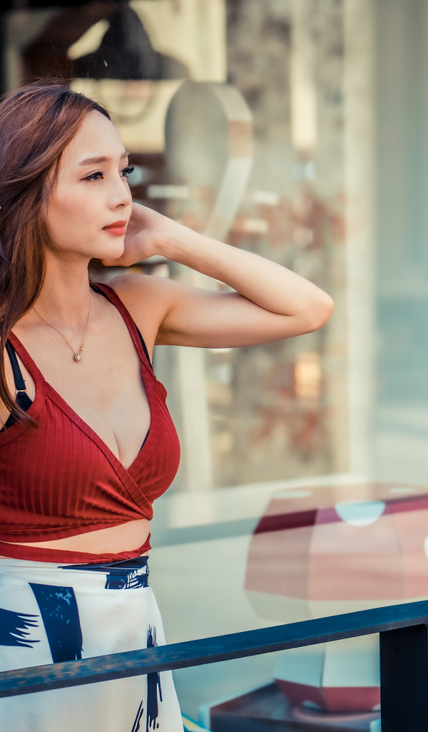 Нежная девушка азиатка стоит на балконе 