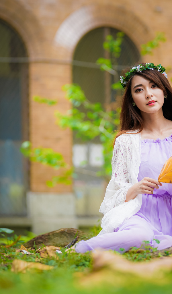 Девушка в красивом платье сидит на траве 