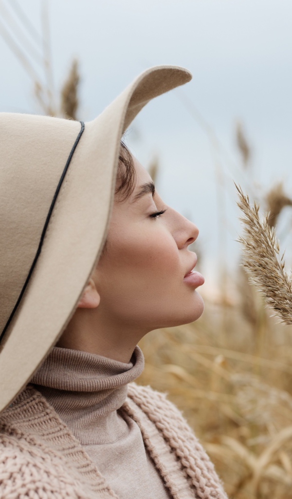 Девушка в шляпе с закрытыми глазами держит колосок 
